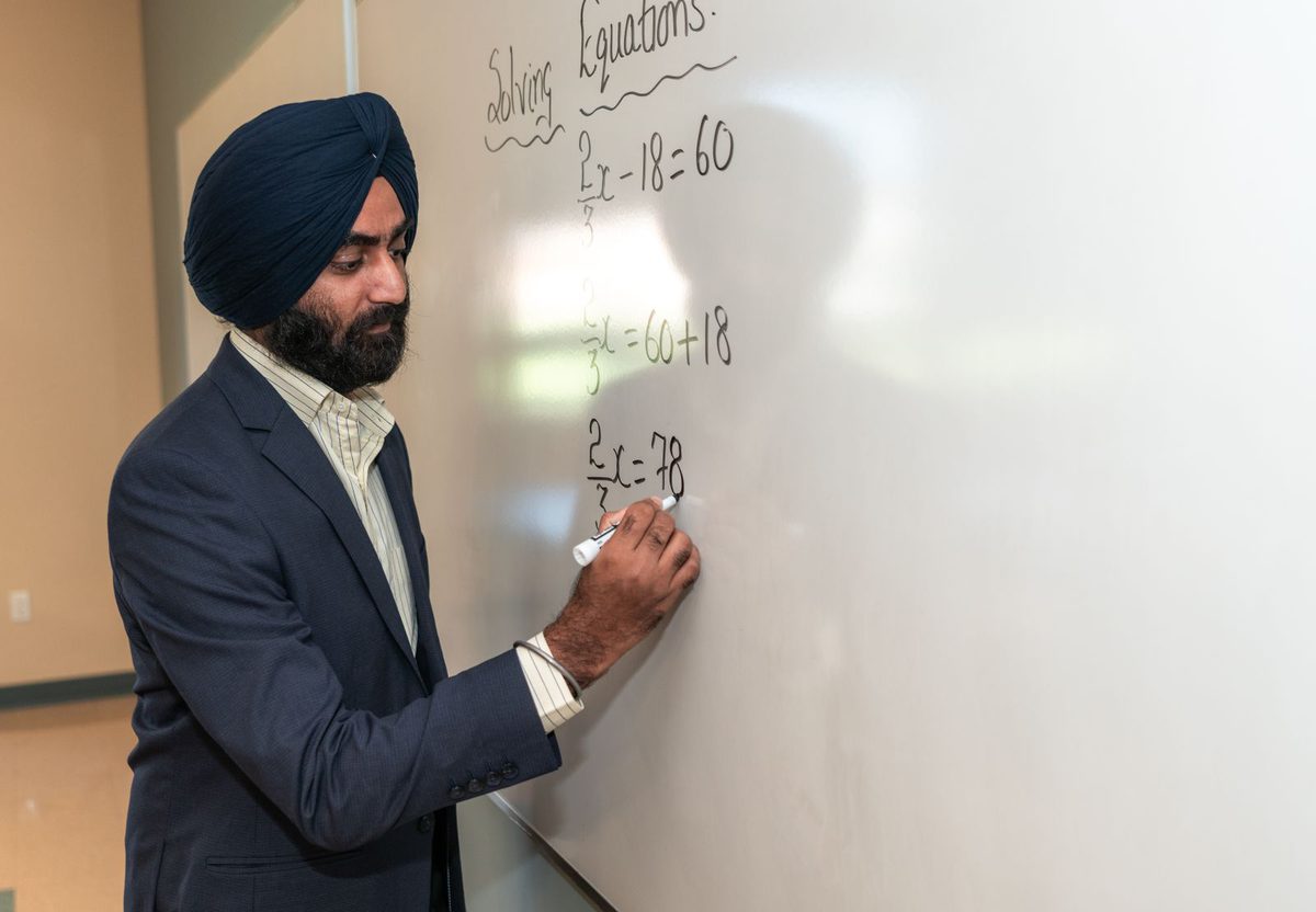 A teacher solving equations on a whiteboard